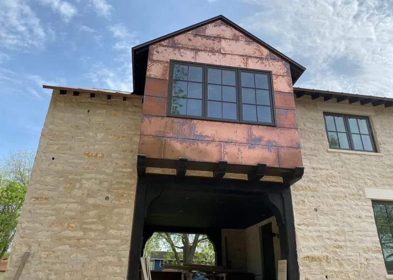 Copper metal panel facade on a stone building for Roof Repair in Walker